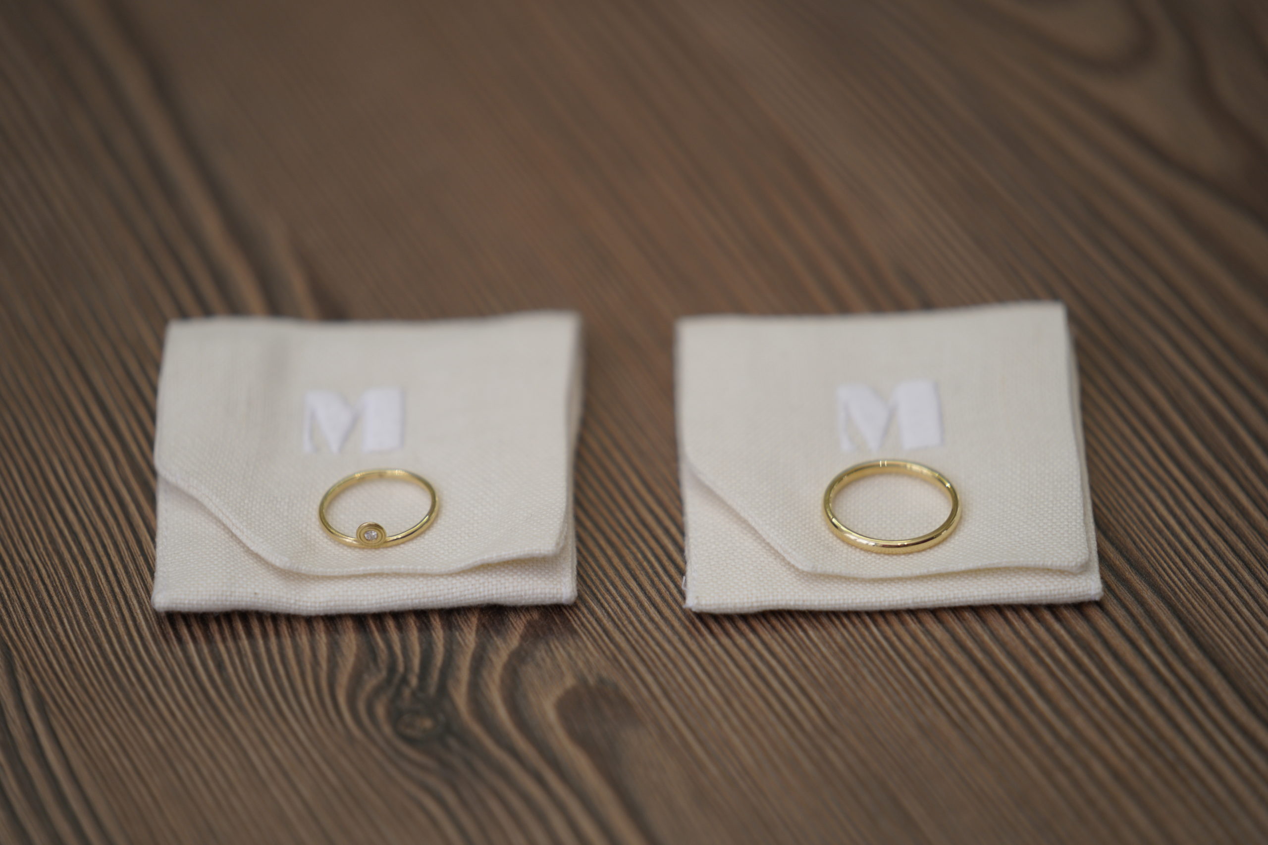 Two delicate gold rings resting on light fabric pouches