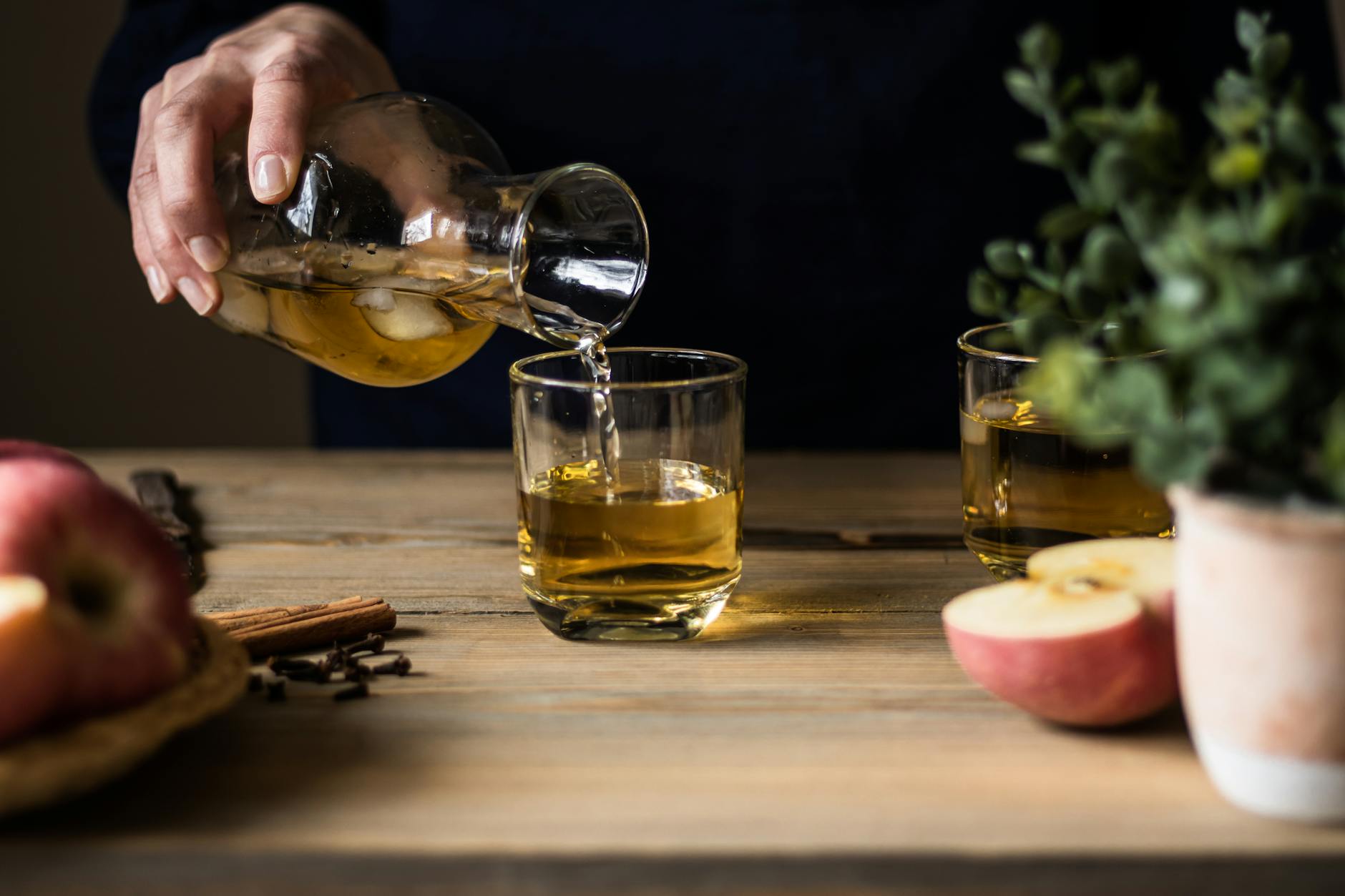 Apple Cider being poured into glasses on a wooden table