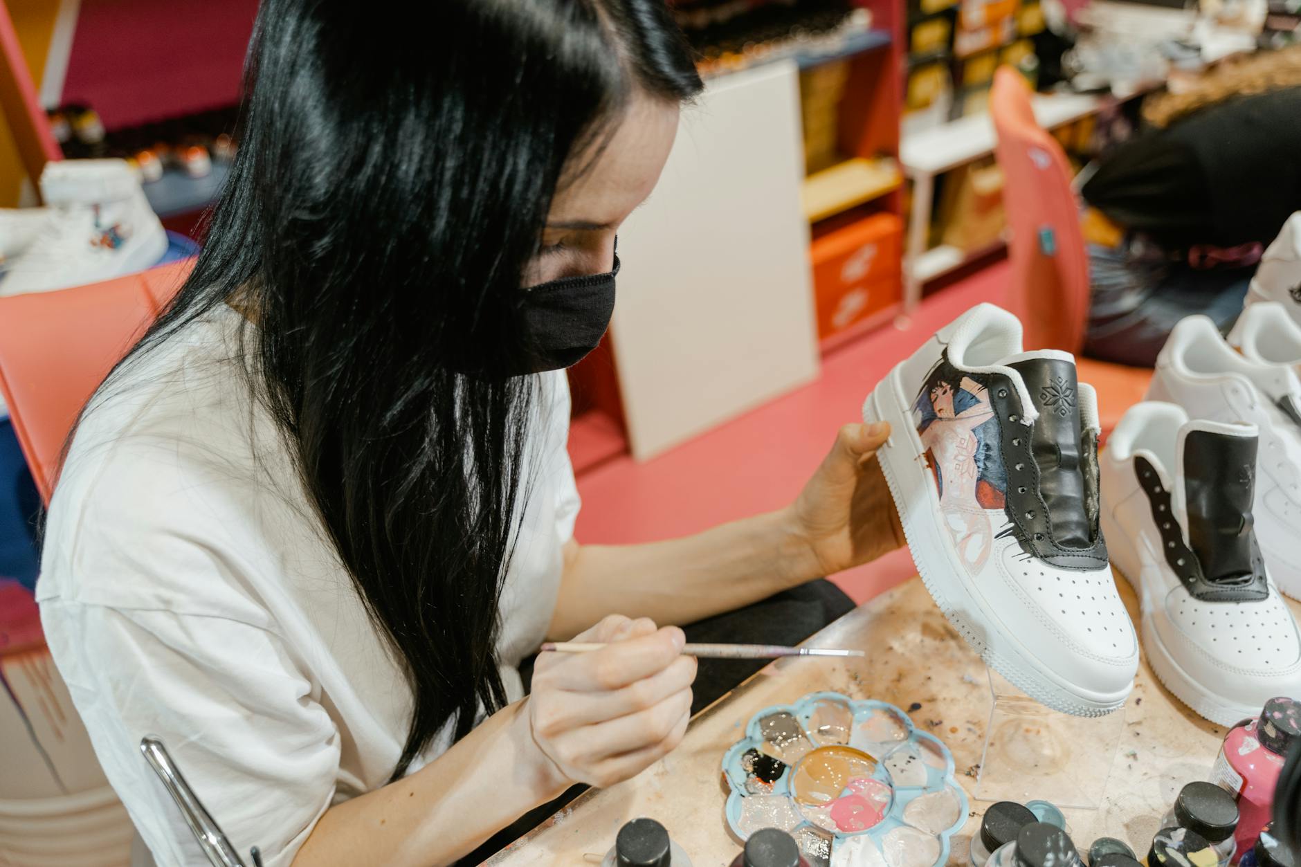 Designer hand-paints a white sneaker with an individual design in the studio