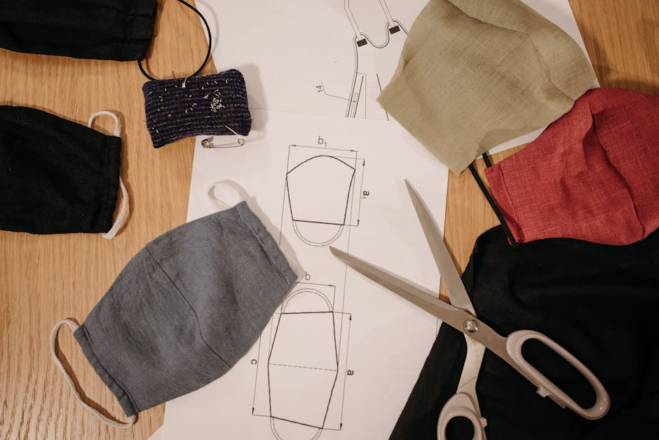 Selbstgenähte Stoffmasken in verschiedenen Farben neben Schnittmuster und Schere auf einem Holztisch
