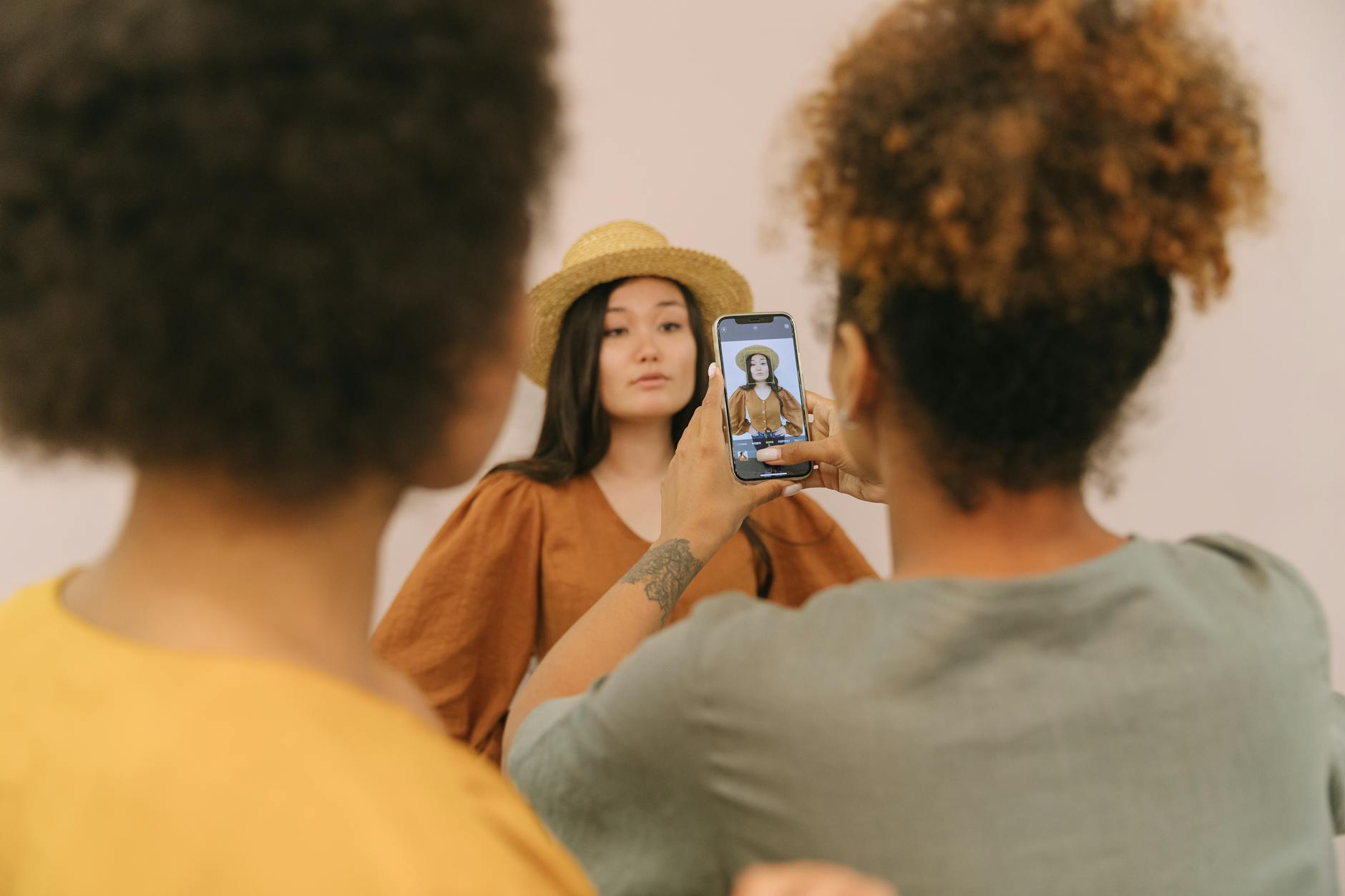 Model im Studio, eine Assistentin fotografiert das Shooting mit dem Smartphone