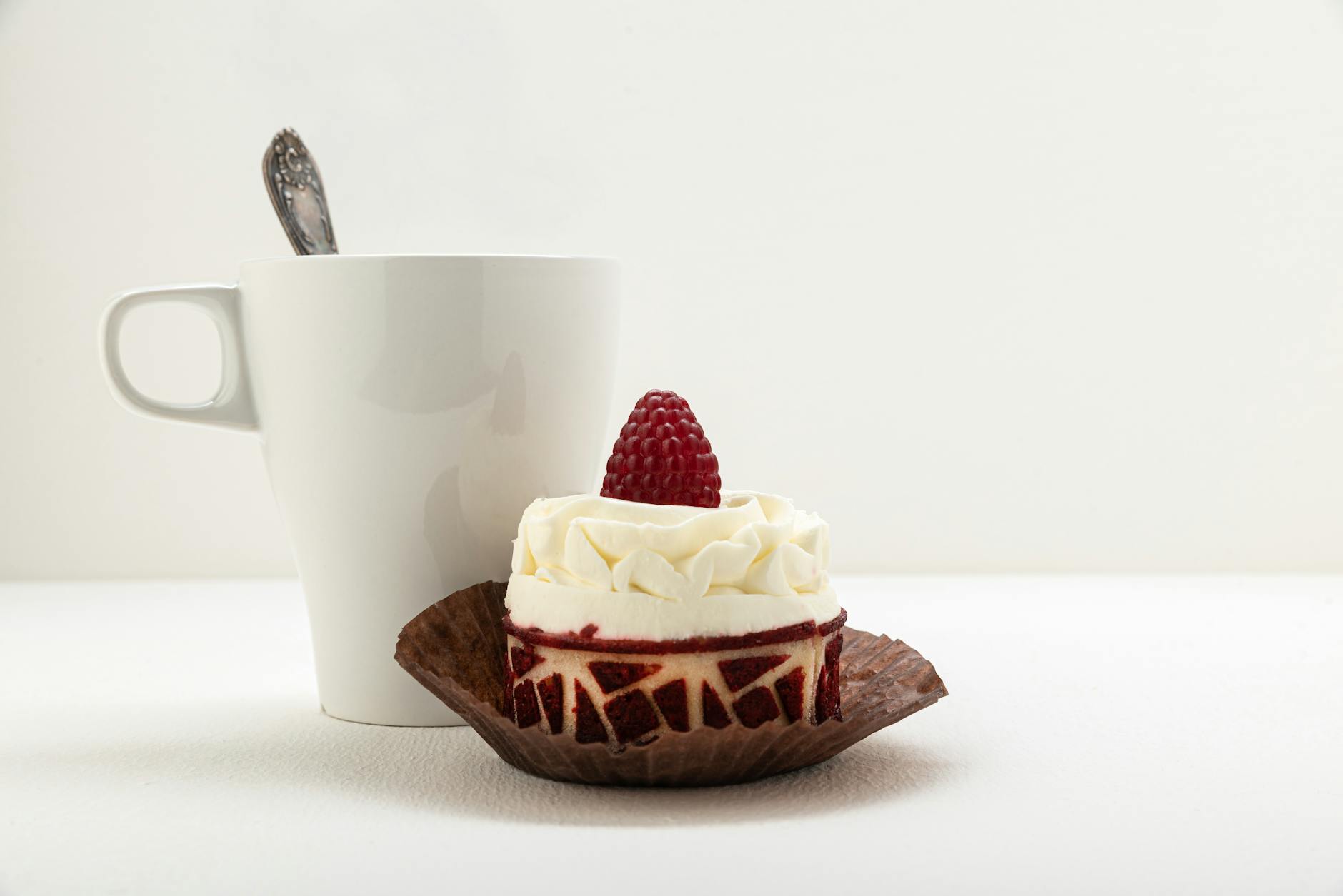 Mug cake topped with raspberries and a cup of coffee on a table