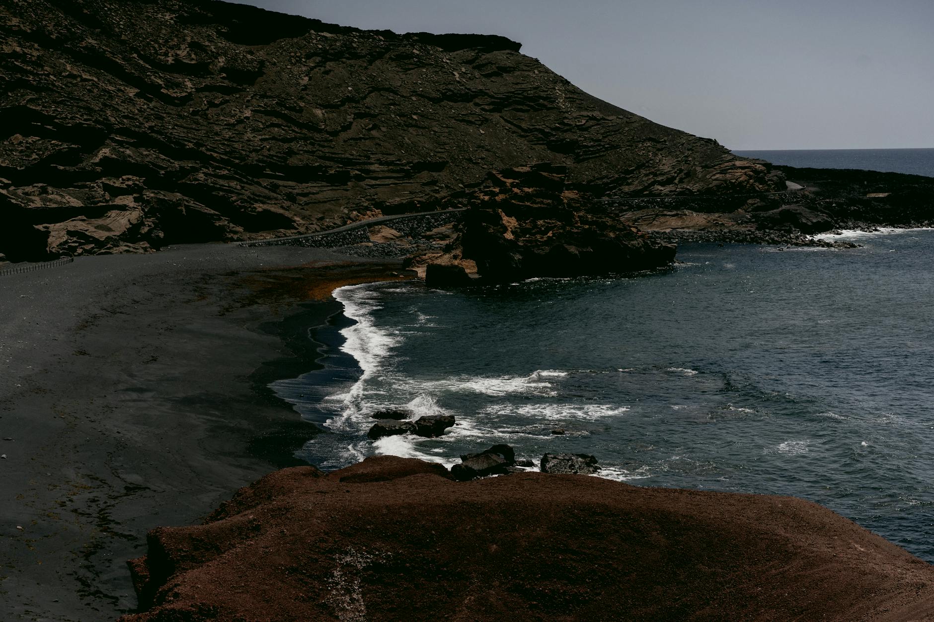Ruhiger schwarzer Vulkansandstrand an der ägäischen Küste im weichen Morgenlicht