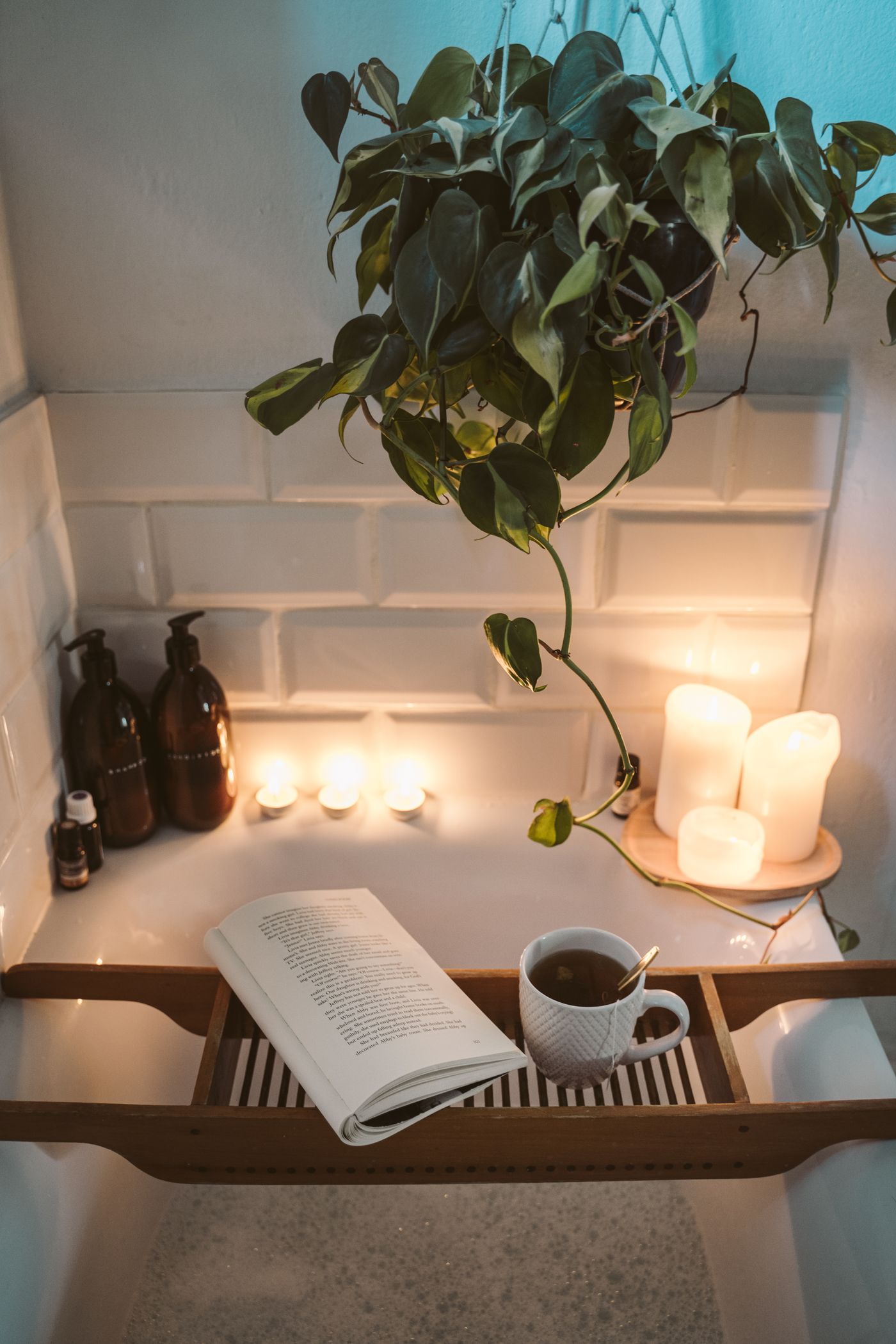 An open book and a cup of tea by warm candlelight