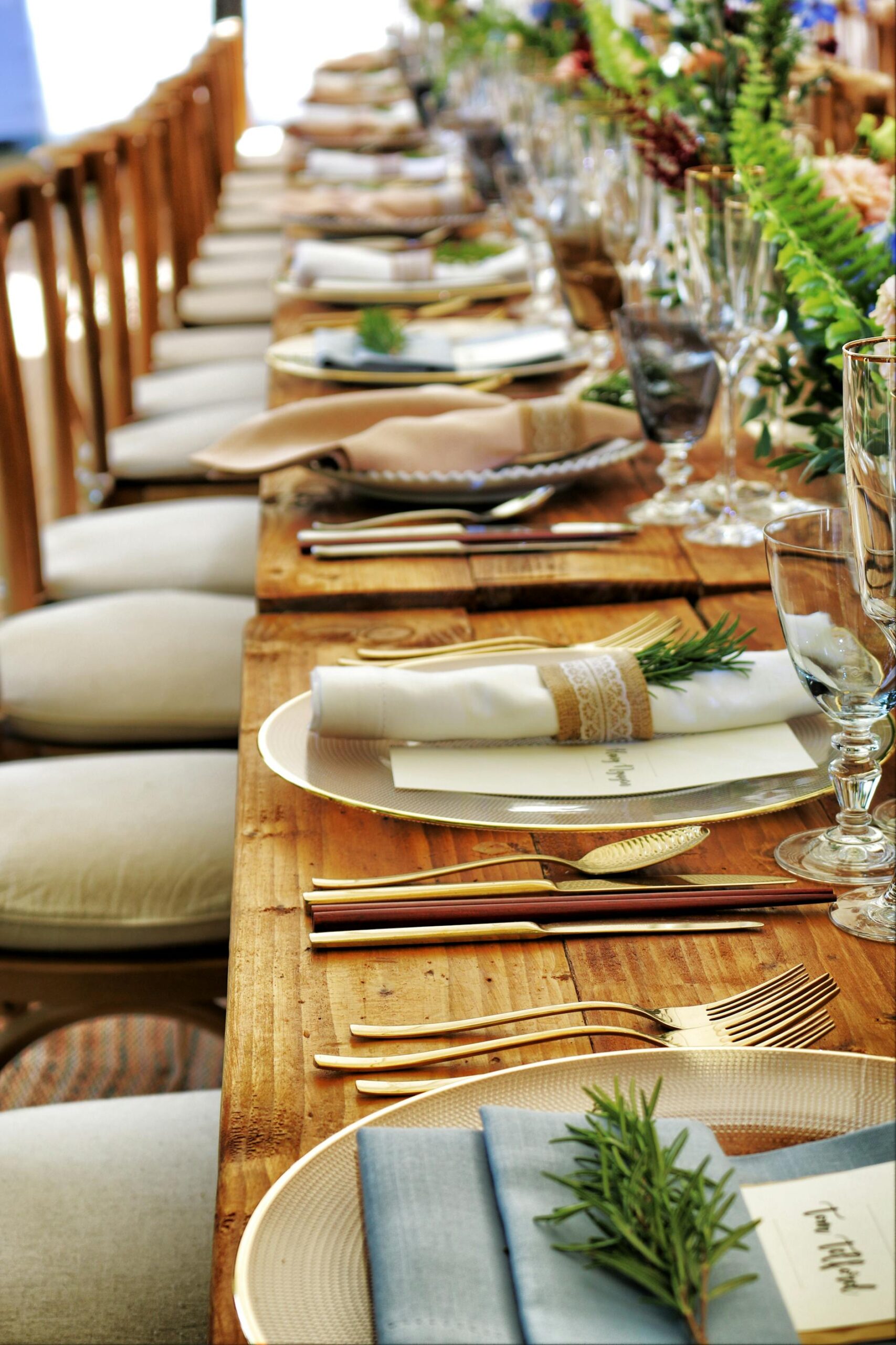 A long, festively set wooden table with linen napkins and gold cutlery
