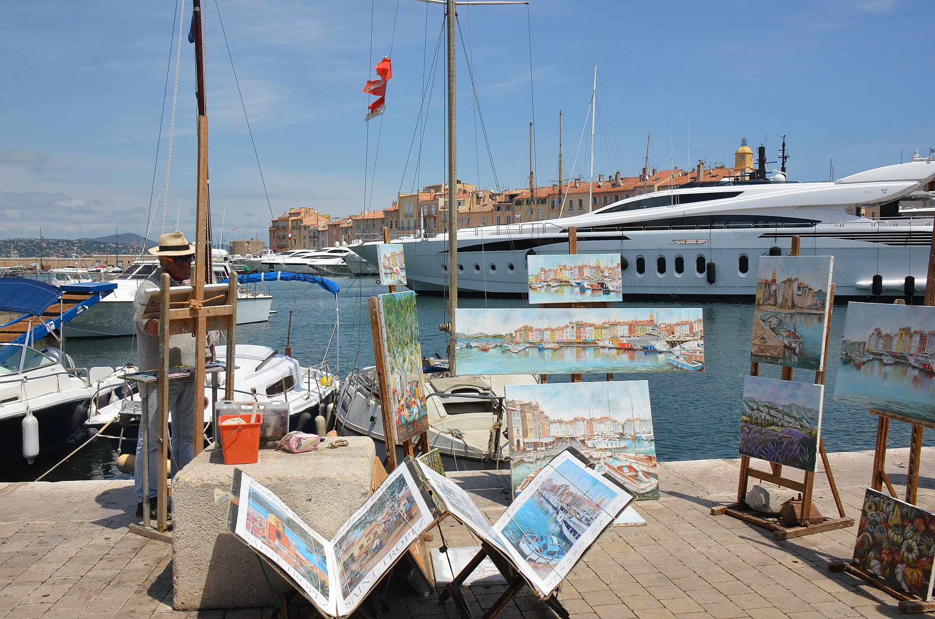 The old port of Saint-Tropez: painters at their easels in front of moored yachts and the ochre façades of the old town