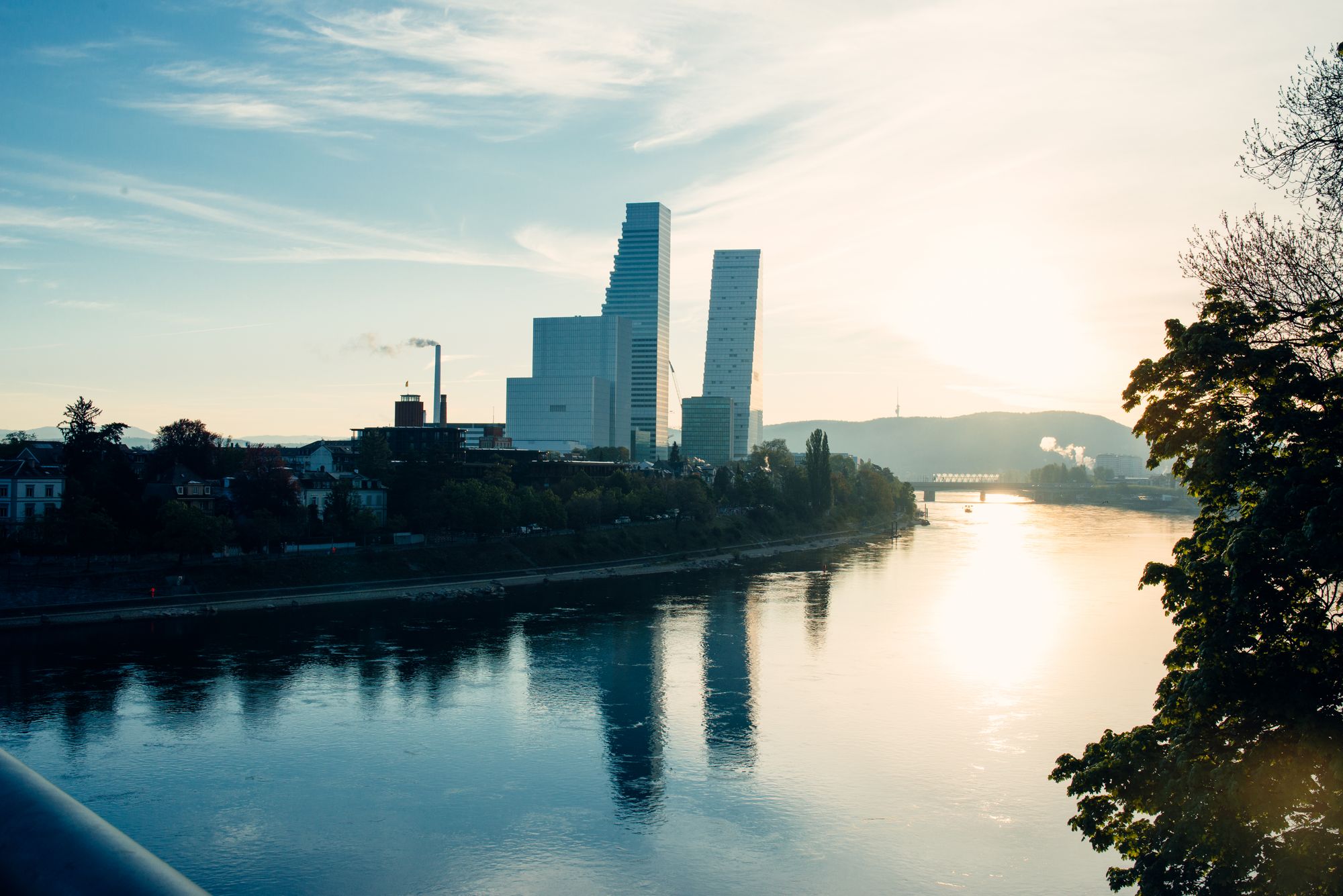 Basel by the Rhine at blue hour, modern towers reflected in the water, vast sky above the city