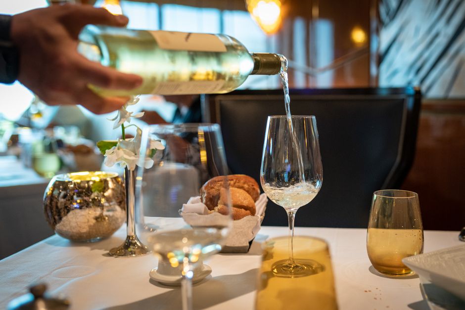Golden unfiltered wine being poured into a glass at a set table