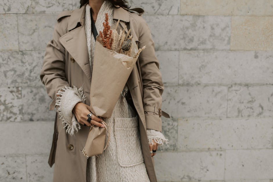 Frau in einem klassischen beigen Trenchcoat vor einer Steinwand