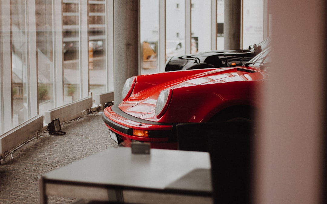 Red sports car in a bright, climate-controlled garage behind glass