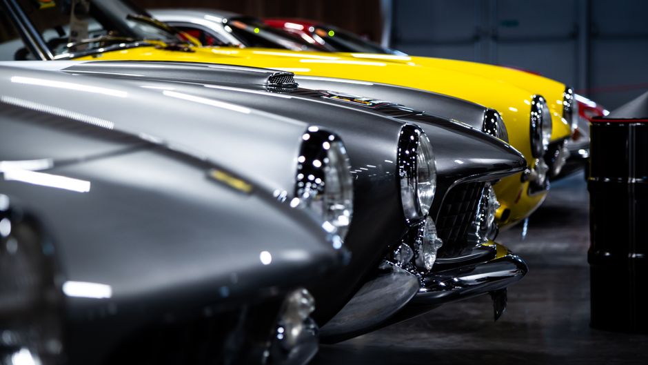 Row of classic sports cars in a dramatically lit hall