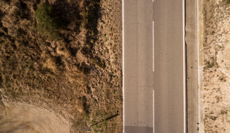Leere Landstrasse mit Kurven durch flache Landschaft im Morgenlicht