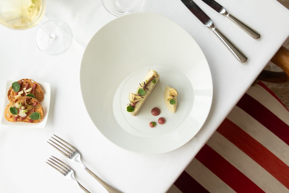 Eleganter Fine-Dining-Teller mit praziser Anrichte und einem Weissweinglas in einem franzoesischen Restaurant