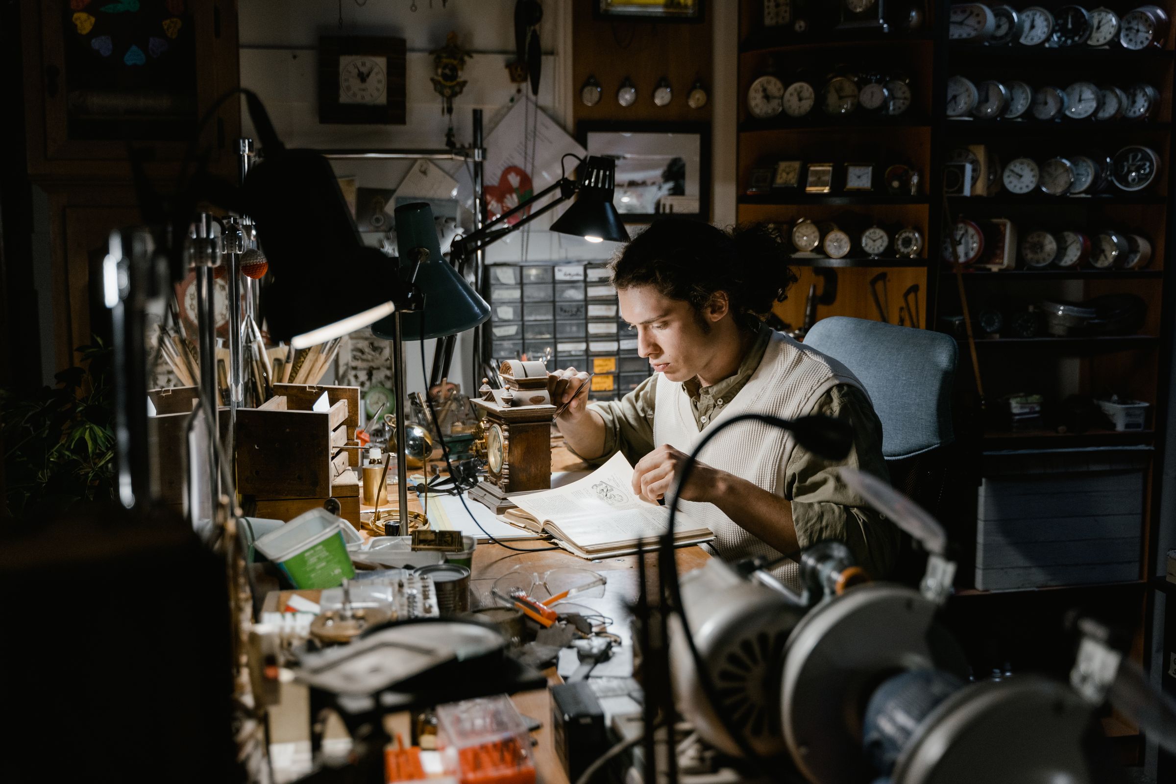 Watchmaker works concentrated at an old workbench in a workshop full of watches and tools