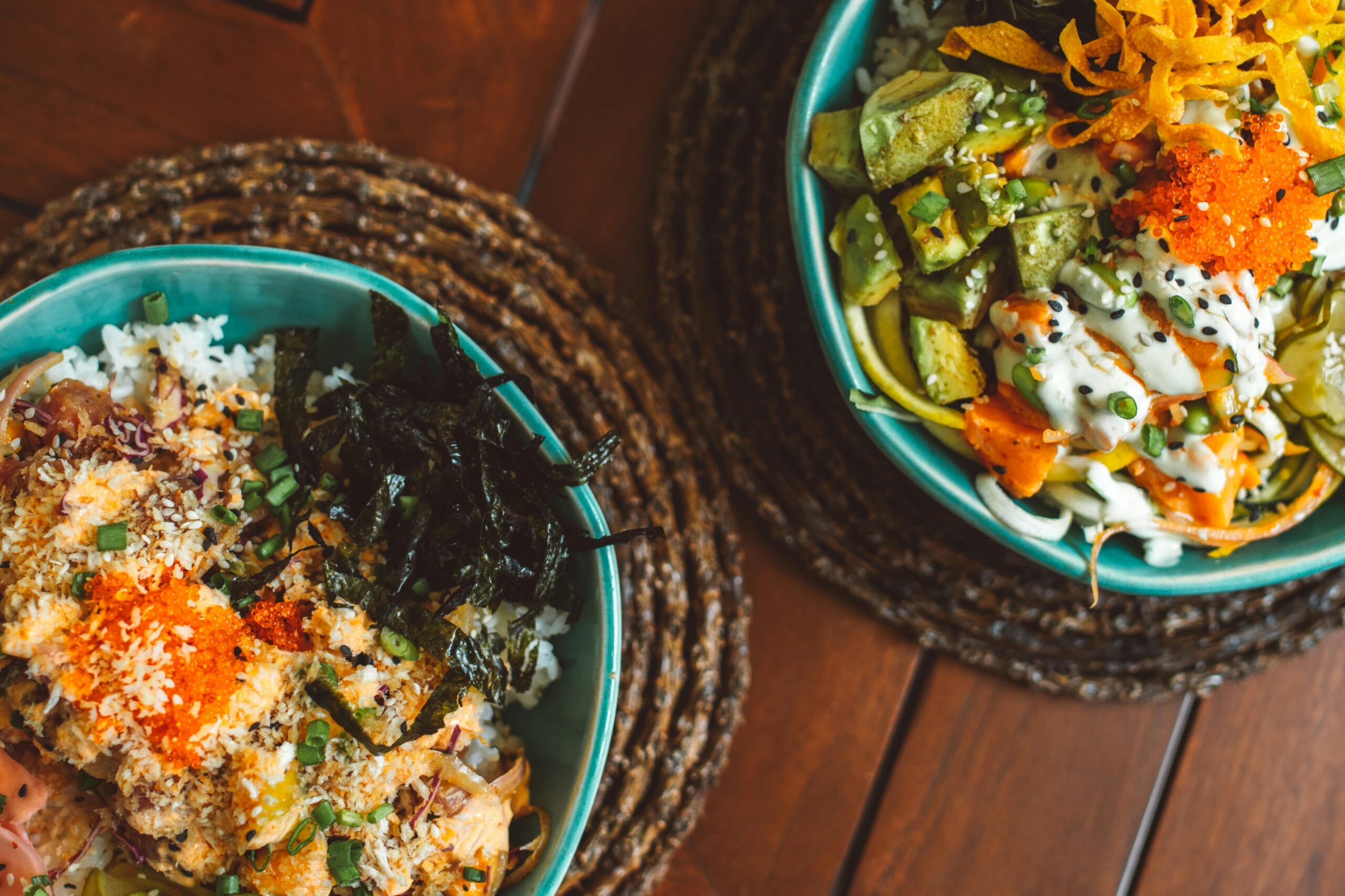 Schüssel mit Avocado-Reis, frischen Kräutern und Limettenscheiben auf einem Holztisch