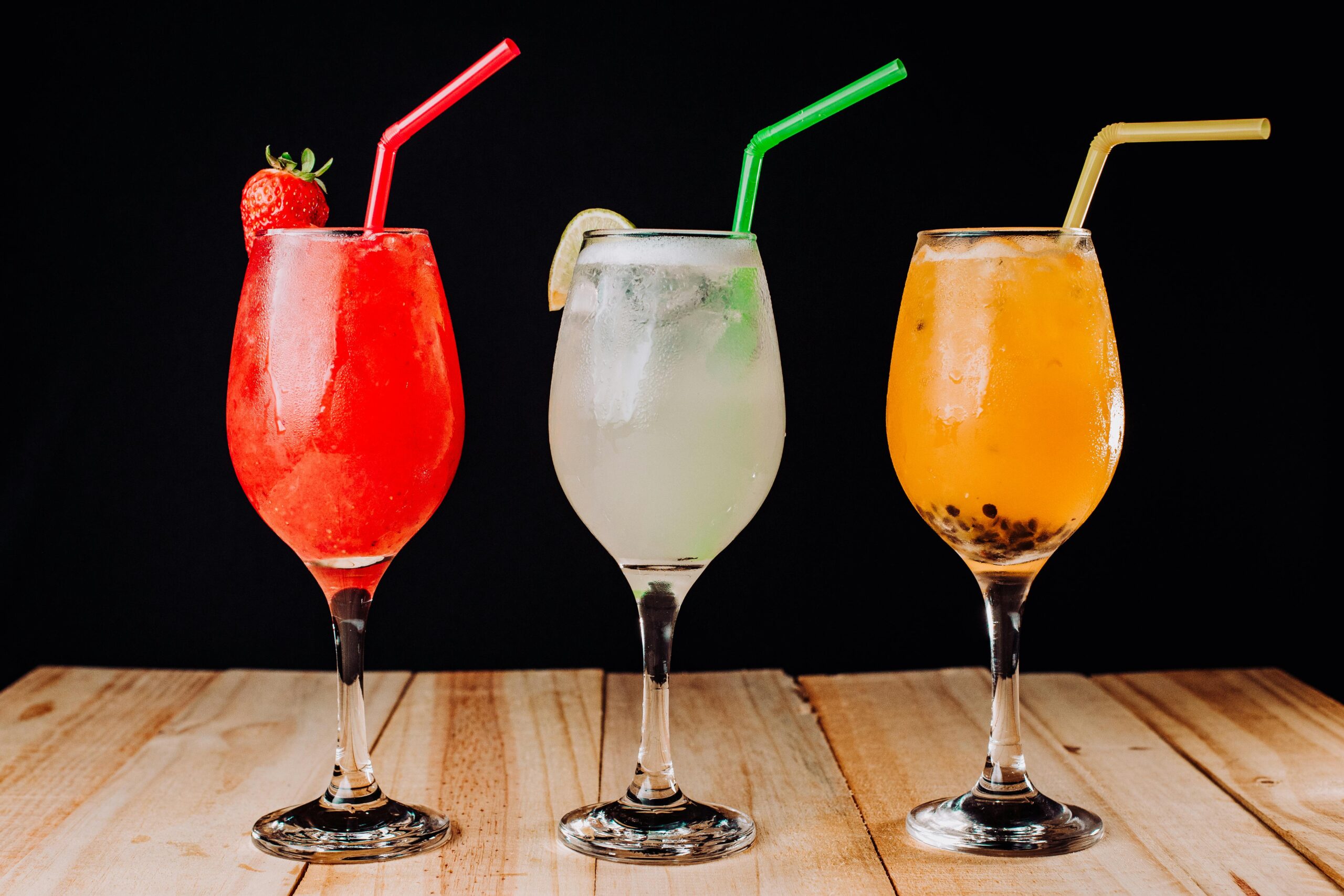 Sommerliche Cocktailgläser mit wiederverwendbaren Trinkhalmen auf einem gedeckten Tisch