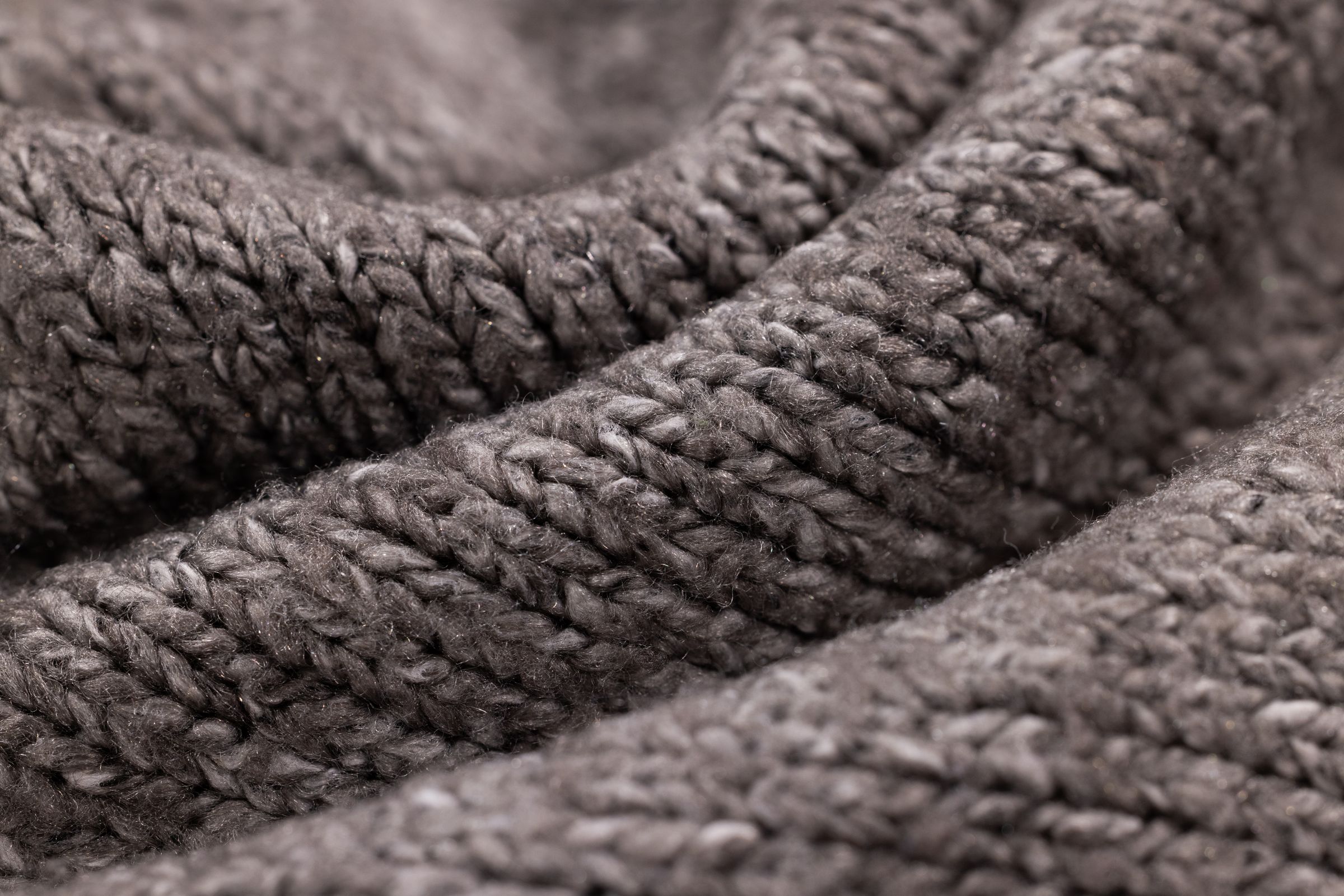 Makroaufnahme einer dunklen Strickoberflaeche mit klar erkennbarer Maschenstruktur, ohne Etikett
