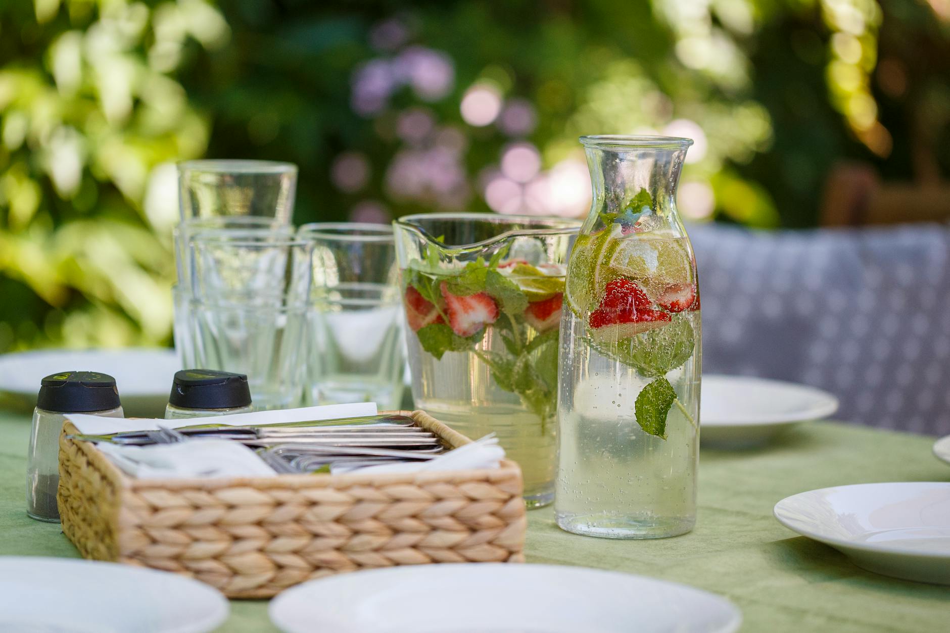 Set of water with lemon and strawberry composing with white plates and tools for eating food