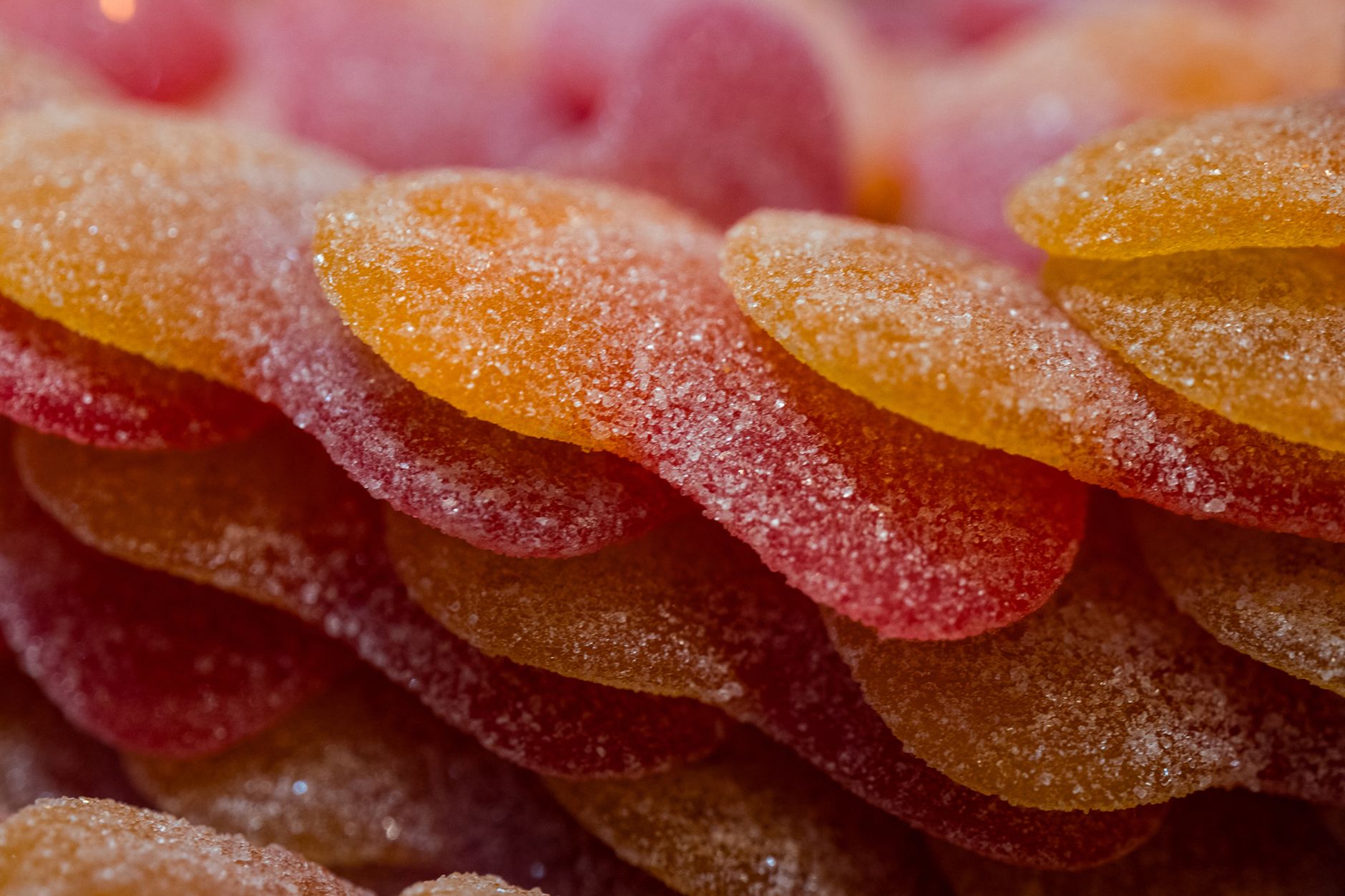 Vibrant macro image of sugar-coated gummy candies with orange and red hues.