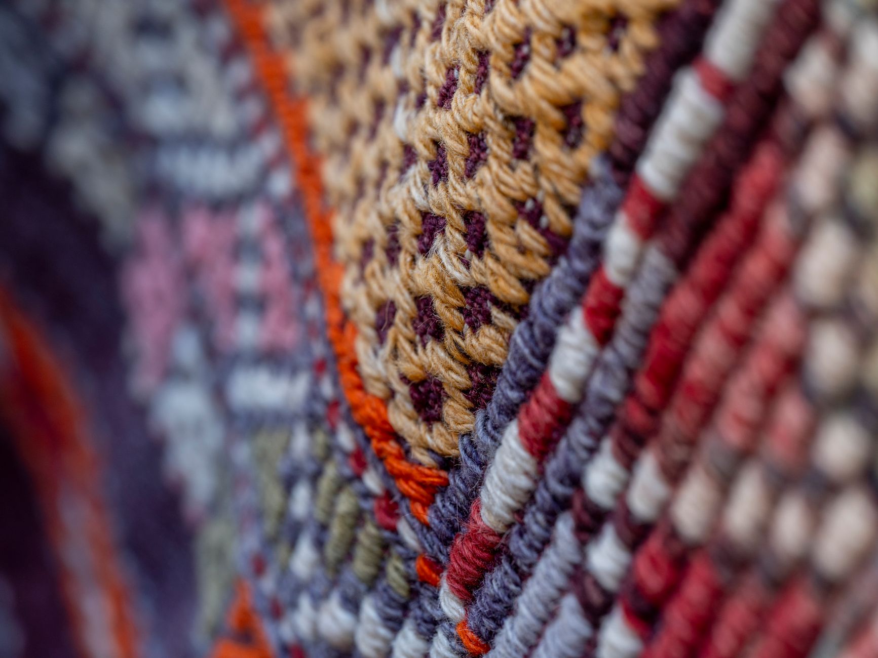 Detailed macro of colorful woven textile showing intricate patterns and textures.