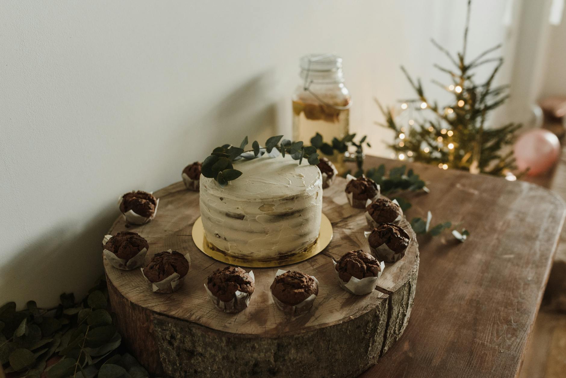 Beautifully decorated chocolate cake with muffins on a rustic wooden table, creating a cozy festive atmosphere.