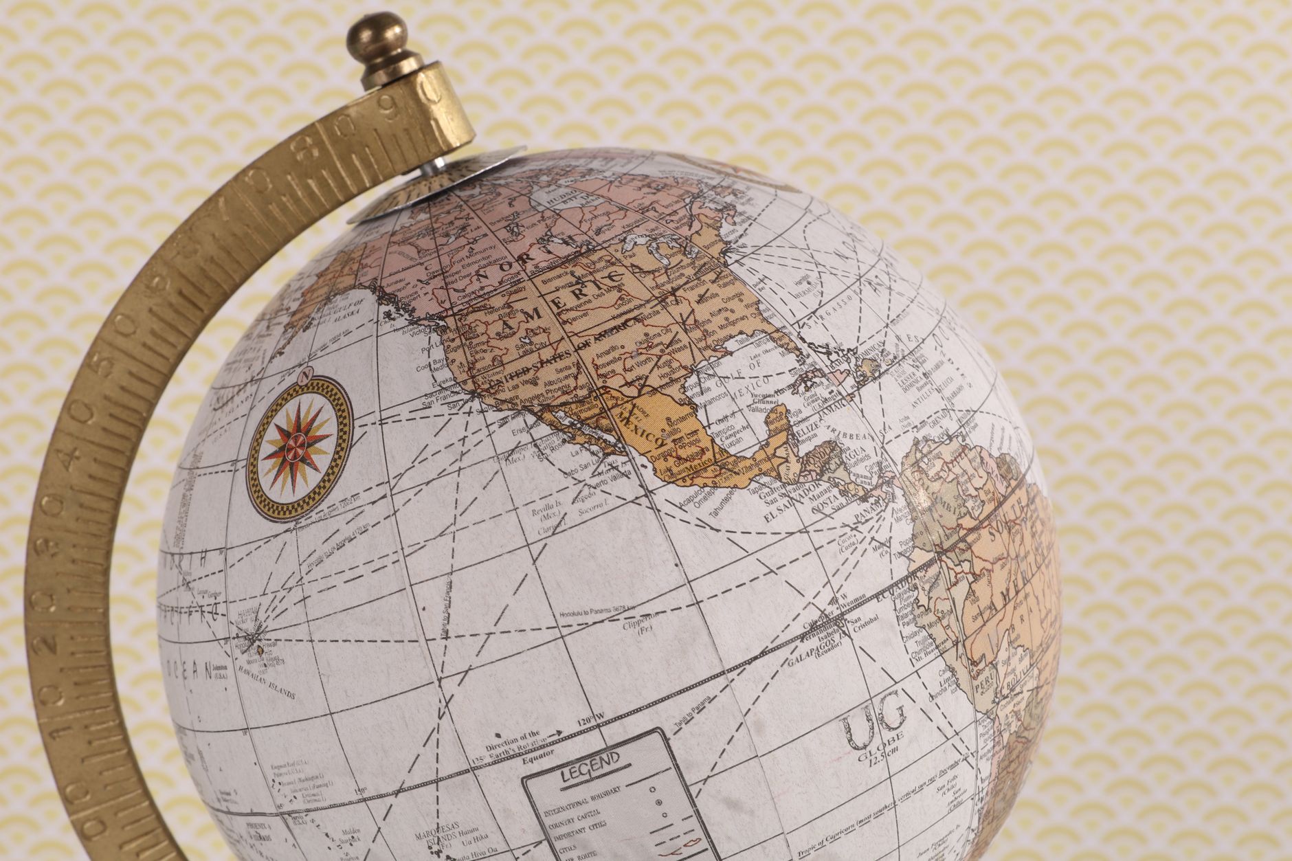 A vintage-style globe showcasing the world map with compass detail on a textured background.
