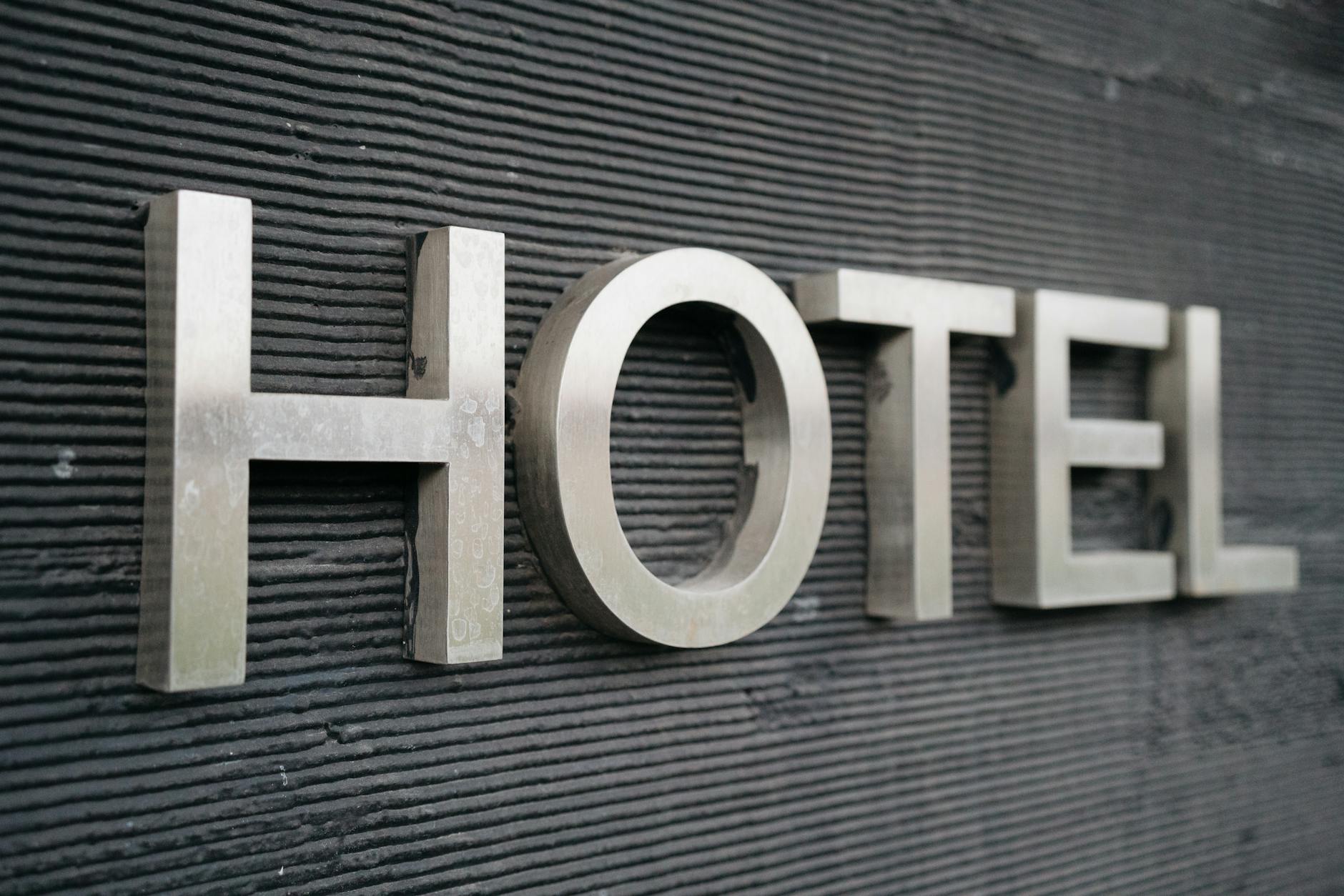 Close-up of a metallic hotel sign mounted on a textured wall.