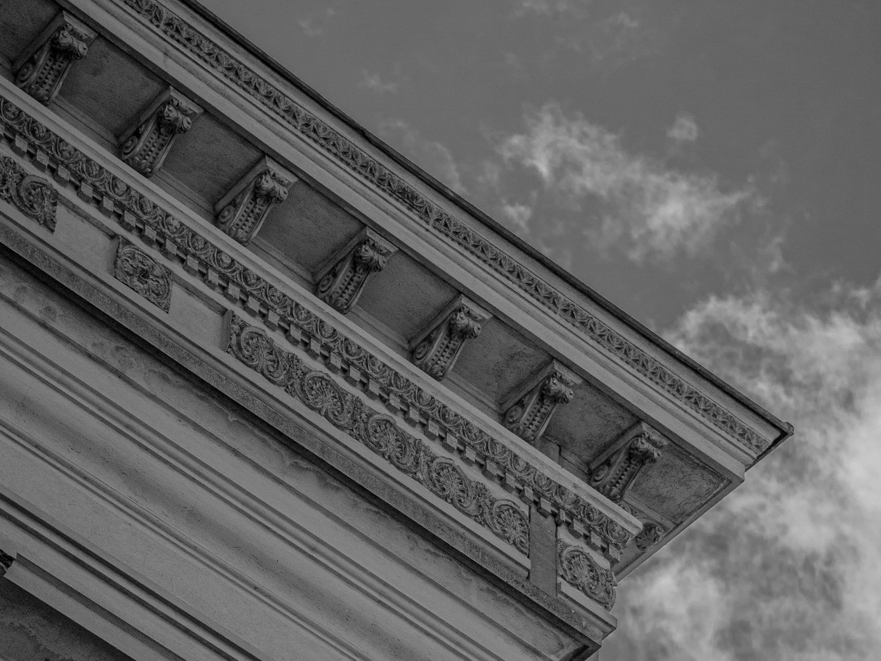 Black and white close-up of a classic architectural facade with ornate carvings.