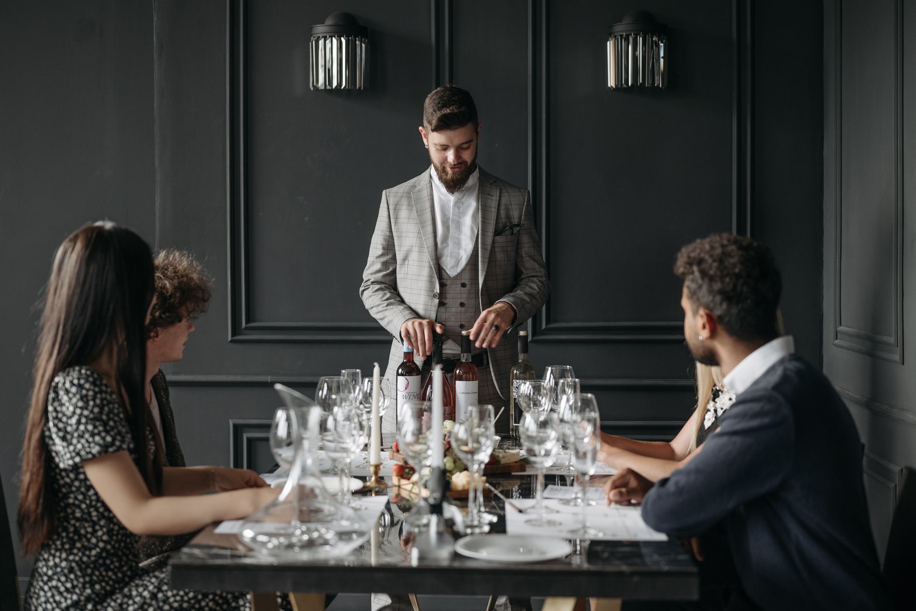 A sophisticated indoor dining setup with a sommelier presenting wine to seated guests.