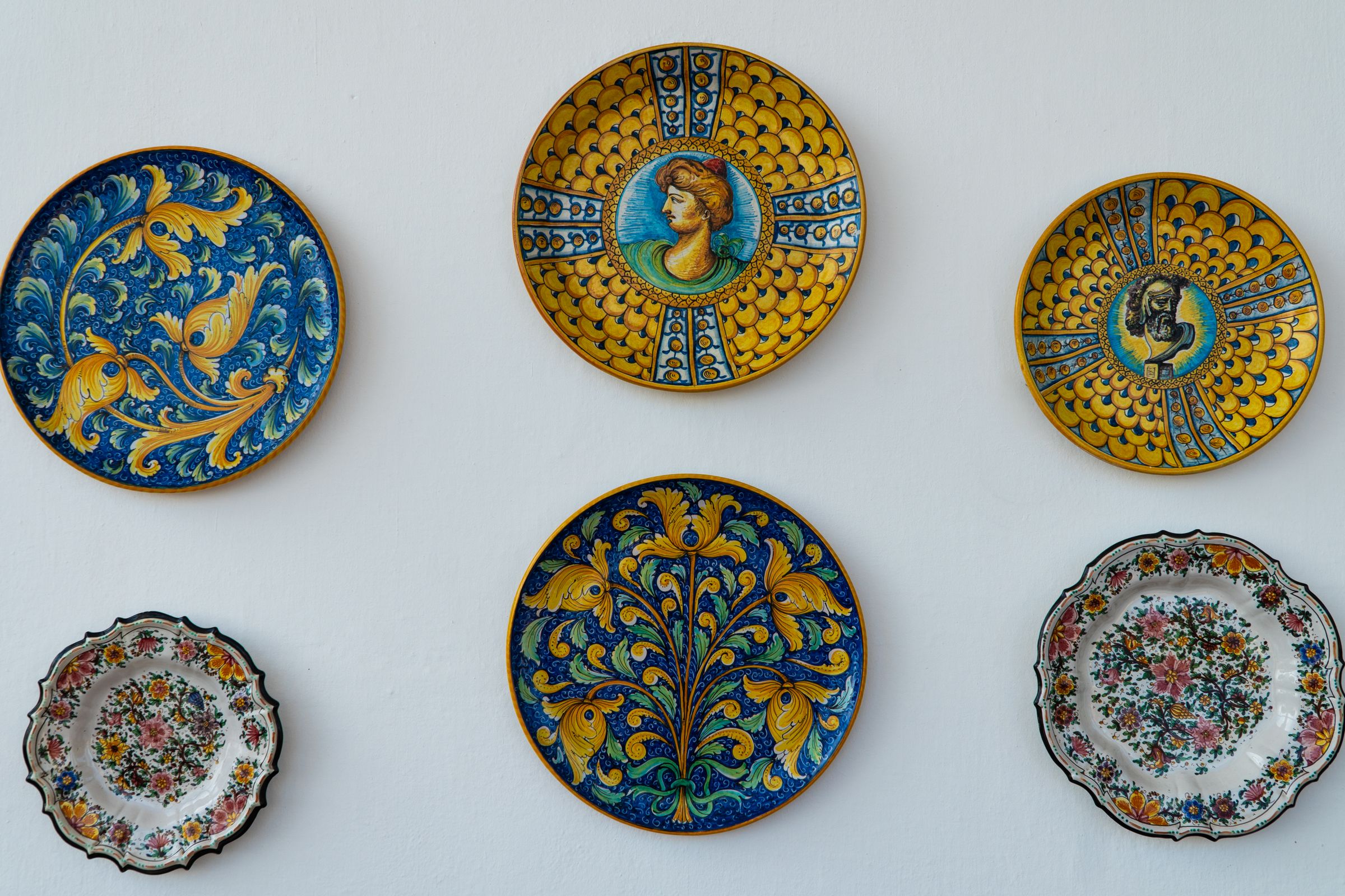Wall adorned with hand-painted Italian ceramic plates in bold colors