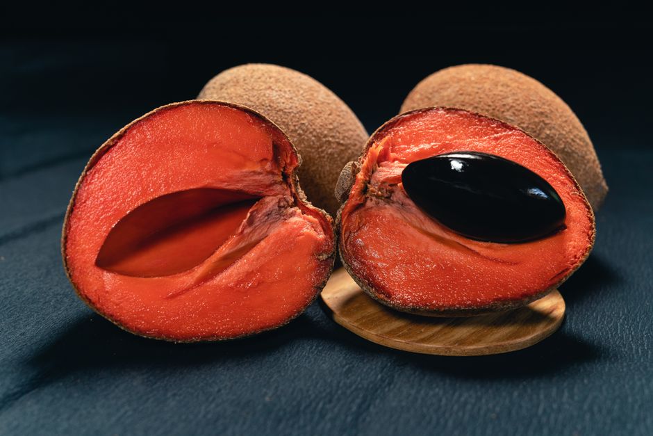Aufgeschnittene Sapote mit charakteristischem dunklem Kern auf einem Holzbrett