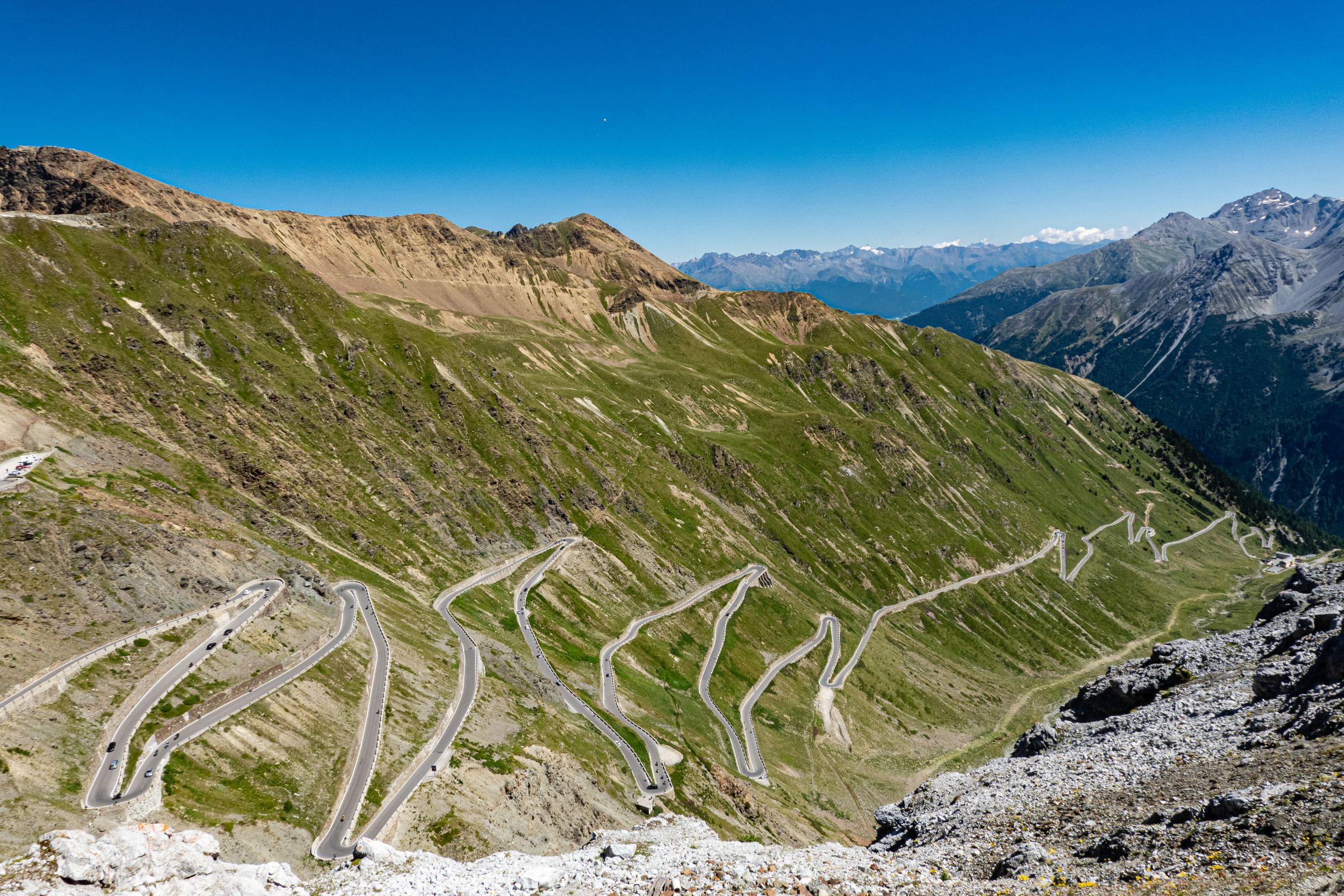 The stacked hairpins of the Stelvio Pass road wind through green slopes and bare rock up to the ridge