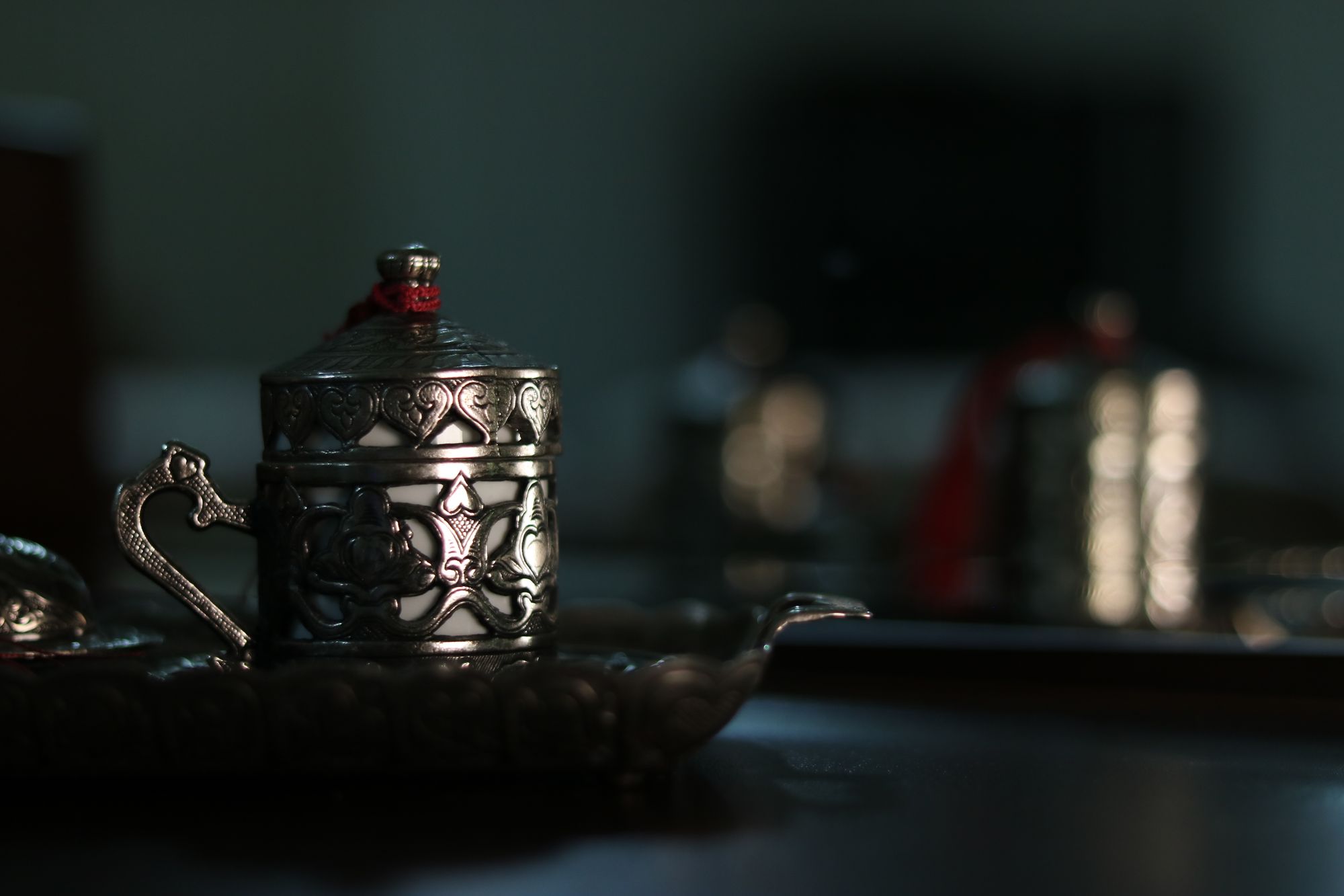 Ornamented silver cup with finely crafted handle in semi-darkness, selective focus on the engraving