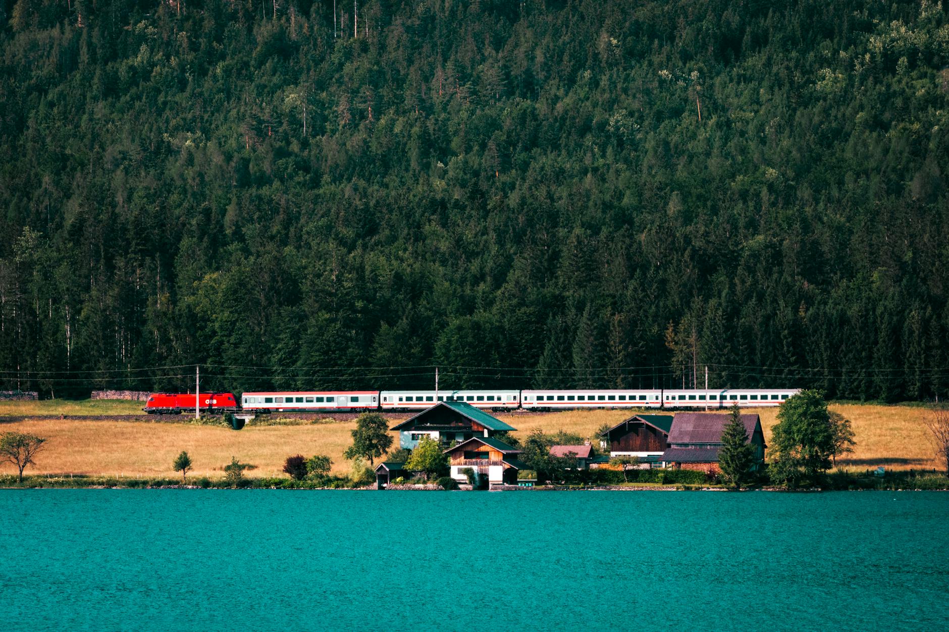 Zug am Seeufer vor Häusern und Wald als ruhiges Motiv für Slow Travel