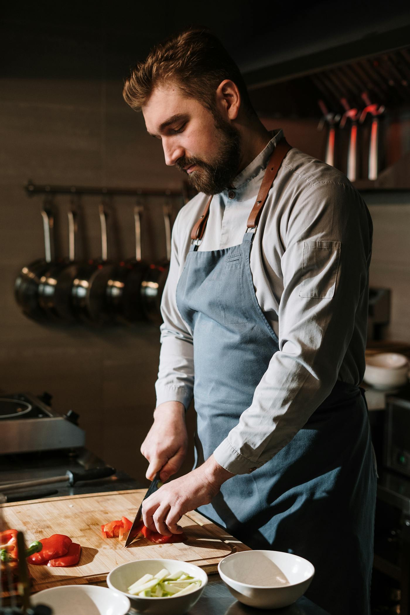 Person cooking and chopping vegetables at a counter in warm light