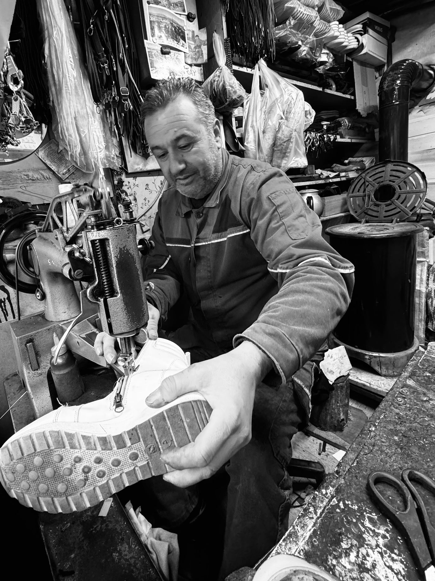 Schuhmacher näht einen handgefertigten Lederschuh in seiner Werkstatt