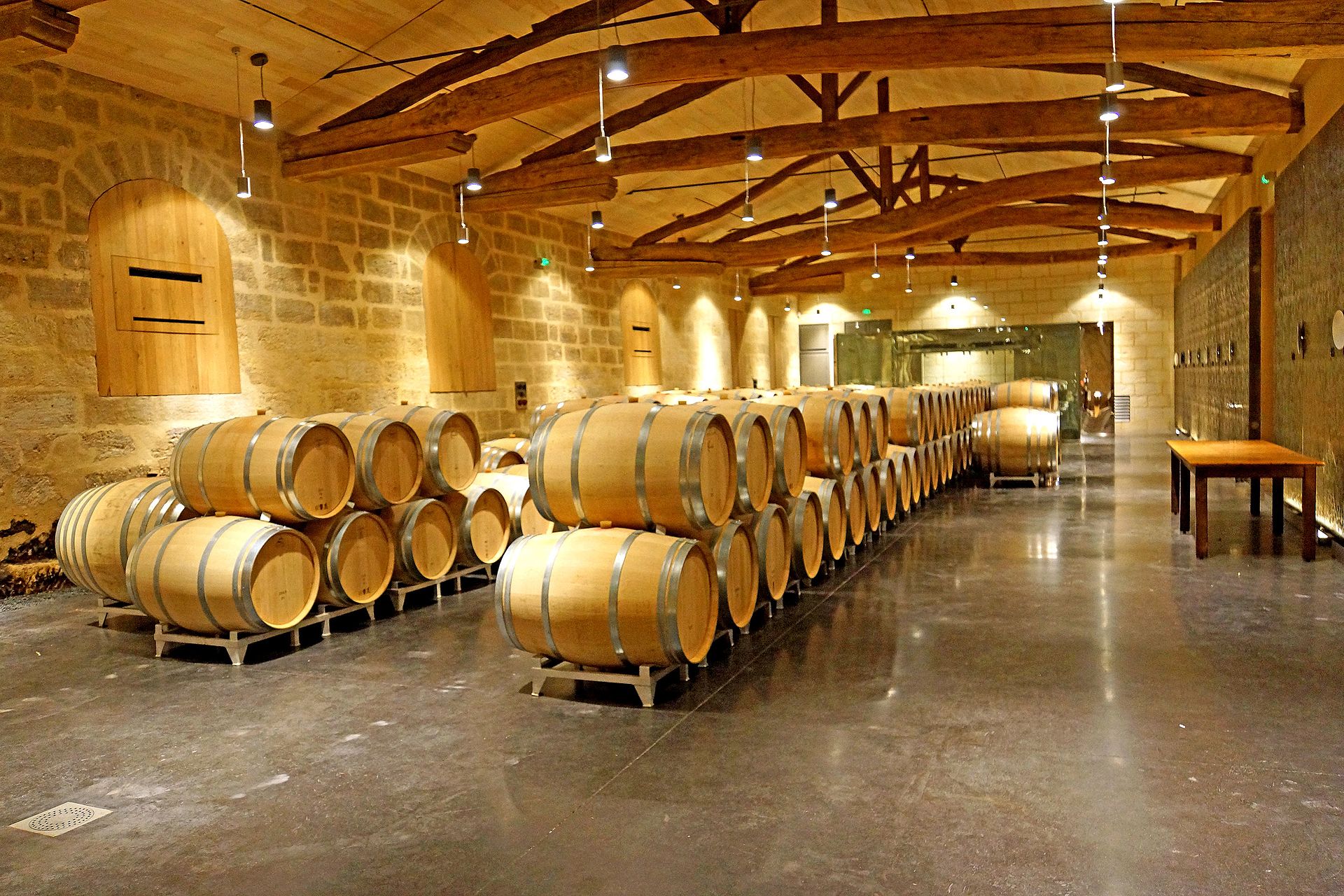 Rows of light oak barrels in a warmly lit wine cellar