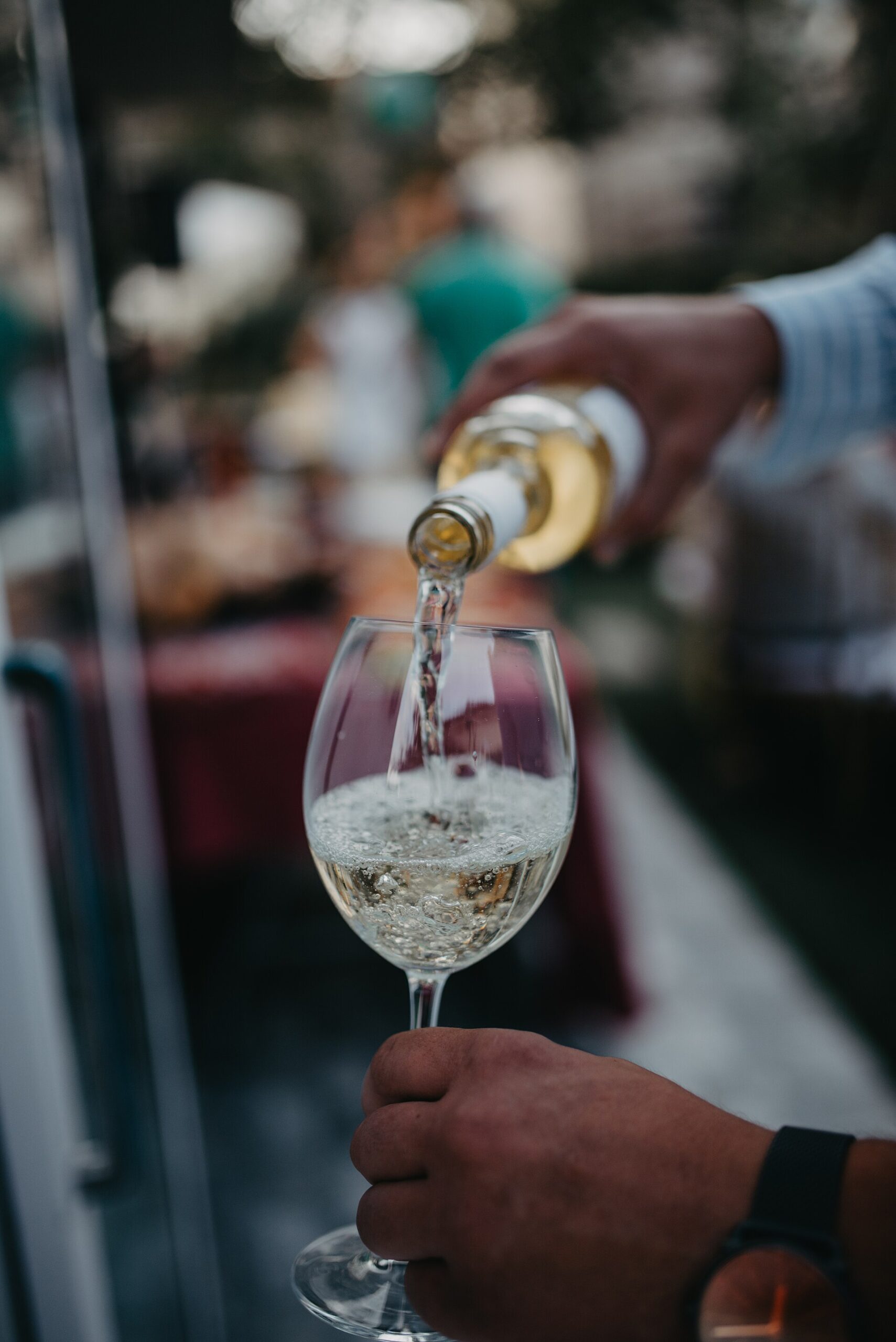 White wine being poured into a glass outdoors in soft light