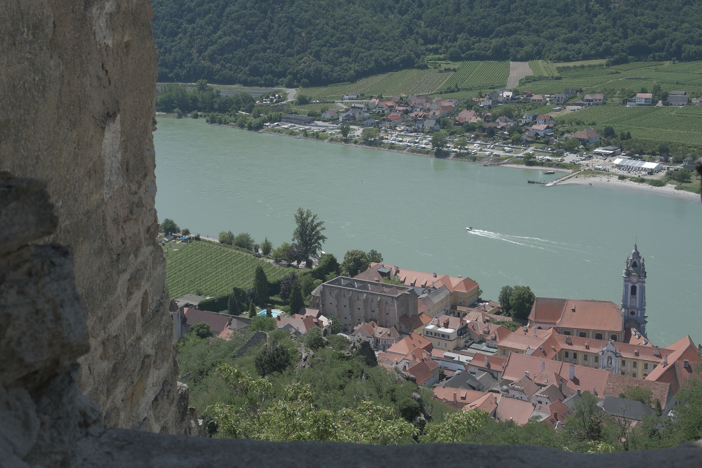 View through an old fortress wall of Dürnstein on the Danube, with vineyards and the blue church steeple