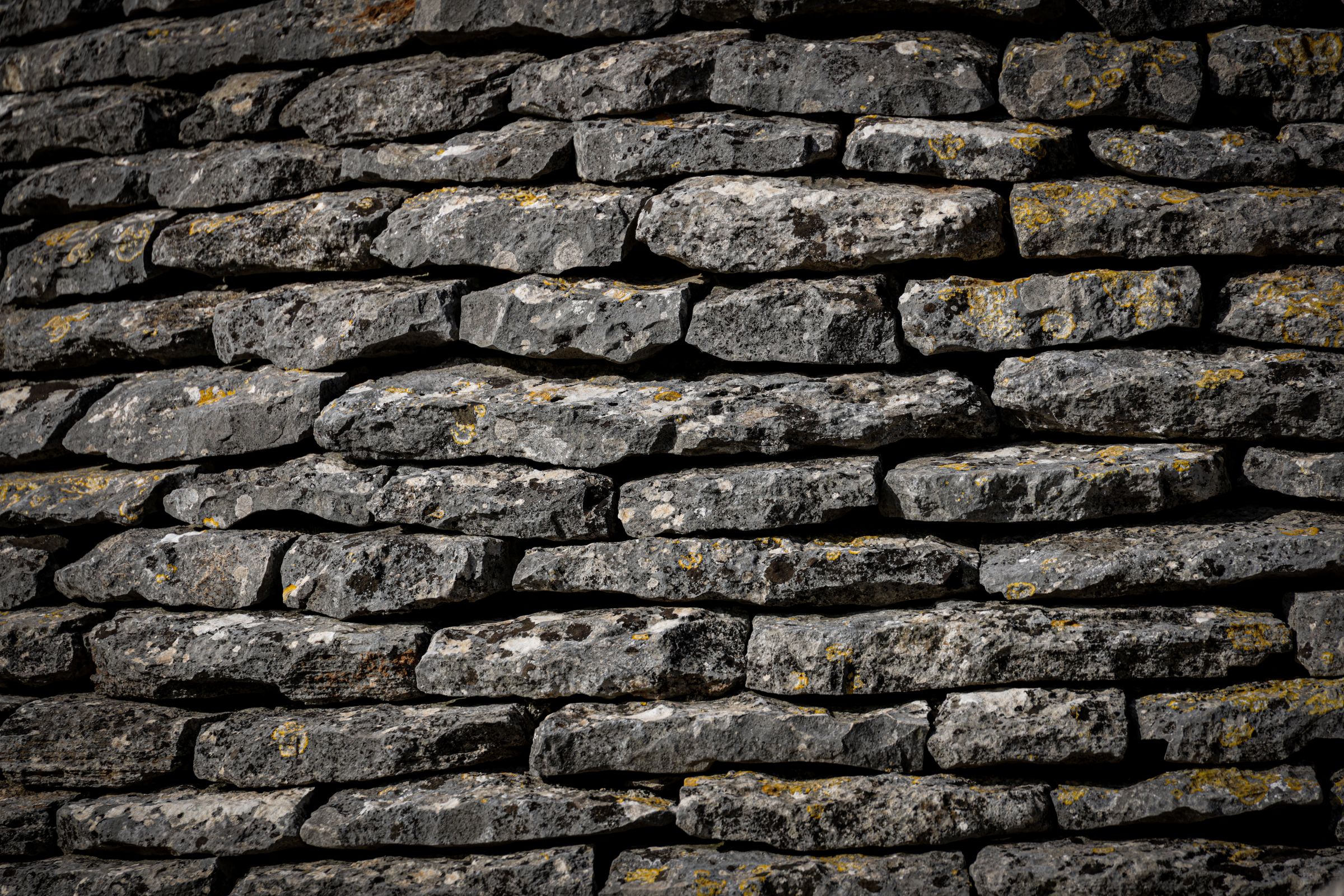 Close-up of a dry-stone wall laid without mortar, lichen growing on the stones