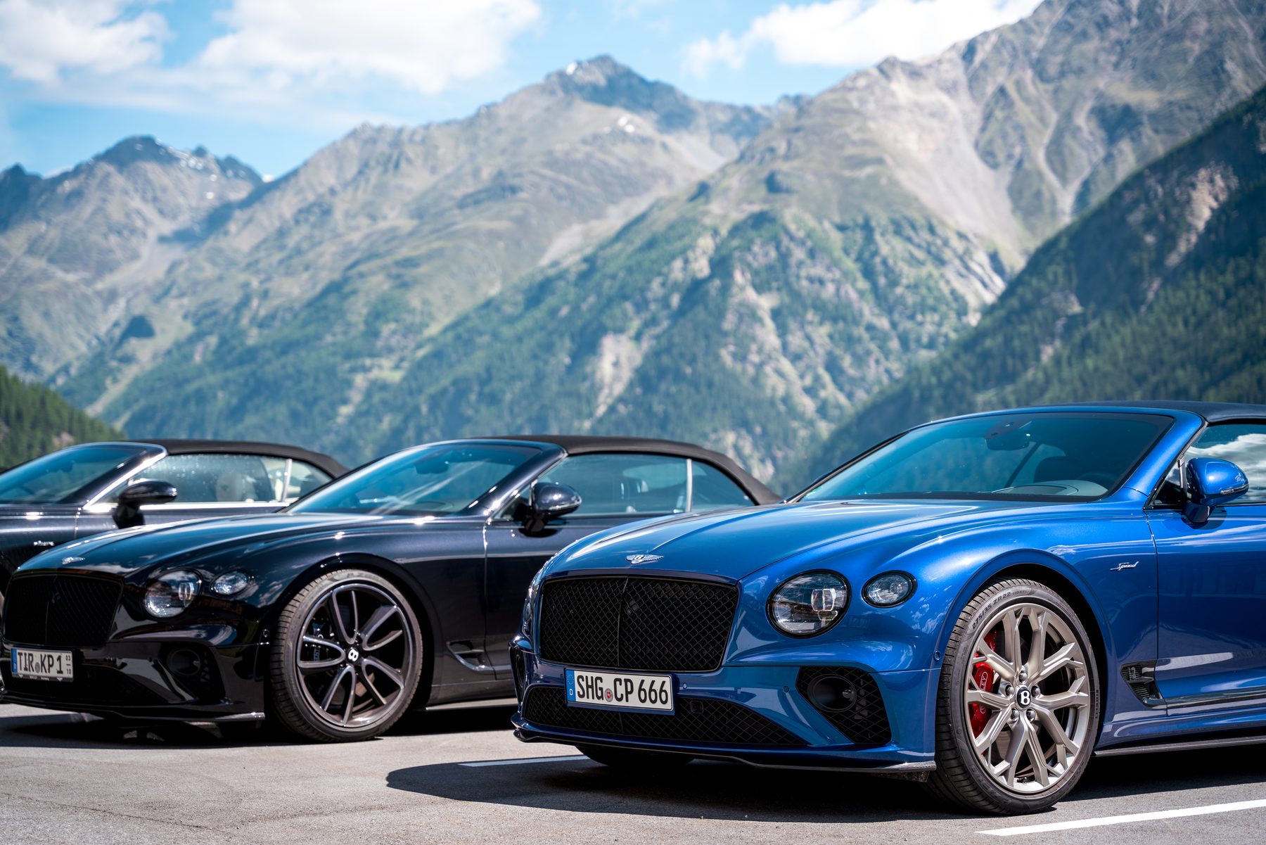 Blue Continental GTC S and a black Bentley against a backdrop of high mountains