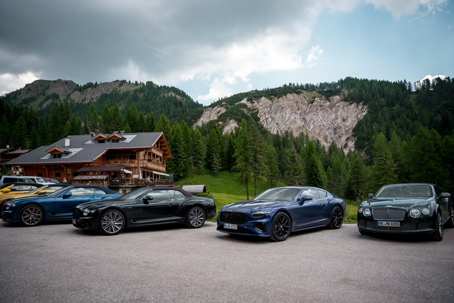 Bentleys parked in front of an alpine hut in the Dolomites, dramatic clouds