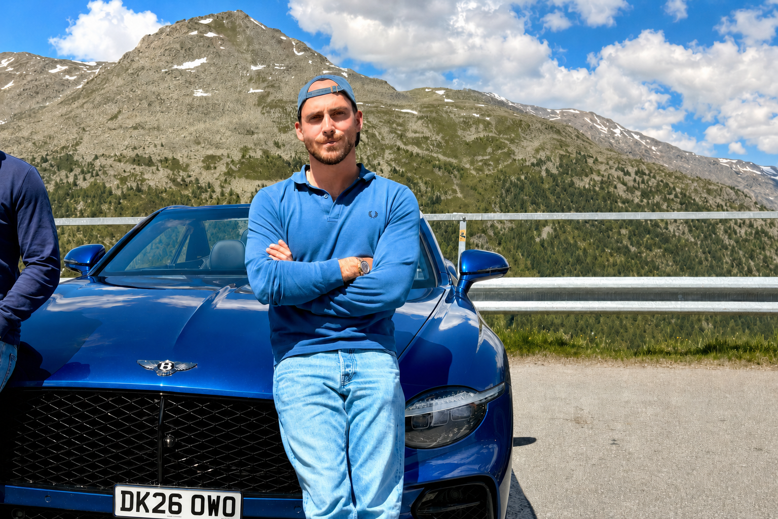 Person leaning casually against a blue Continental GTC S with mountain backdrop