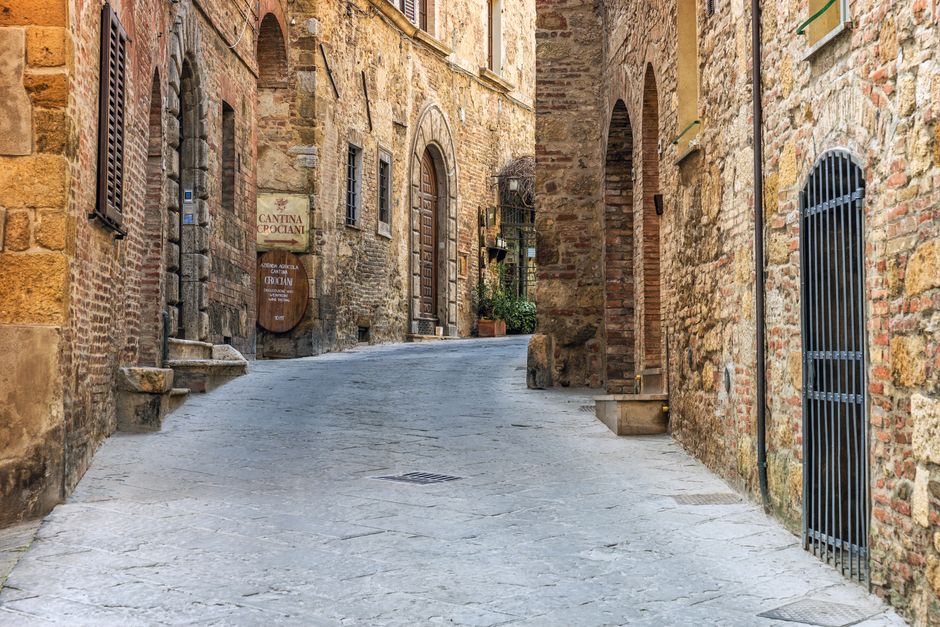 You stroll down a narrow stone street in an Italian hill village at dawn.
