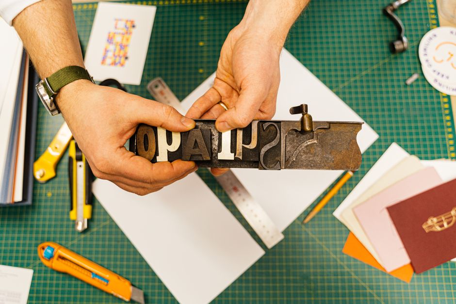 Hände setzen Bleilettern an einem Werktisch