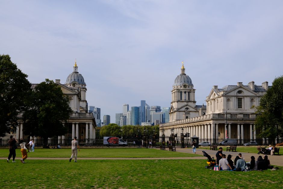 Menschen auf einer Rasenfläche in einem Londoner Park mit klassischer Architektur