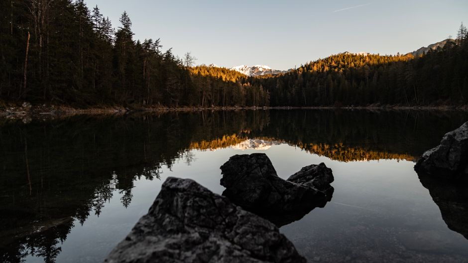 Mirror-smooth lake surface reflecting surrounding mountains