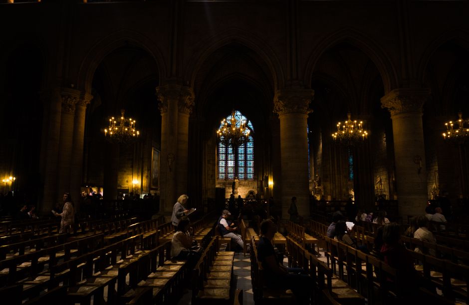 Dimly lit Gothic church interior with arches and stained-glass windows